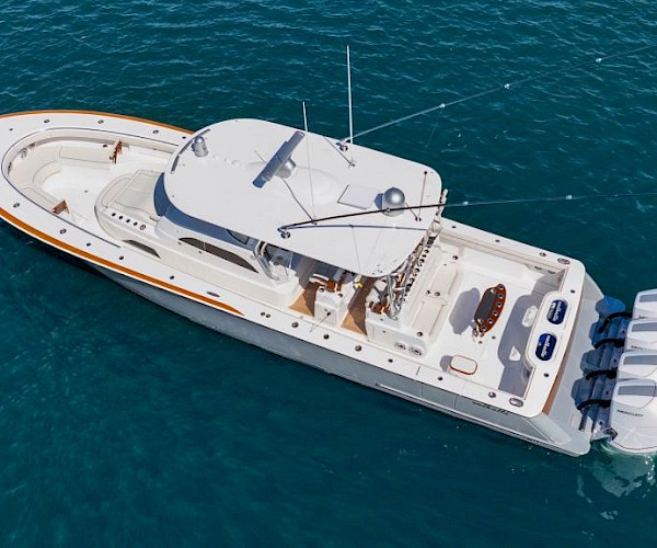 The image shows a large white powerboat with multiple outboard engines, floating on the ocean.