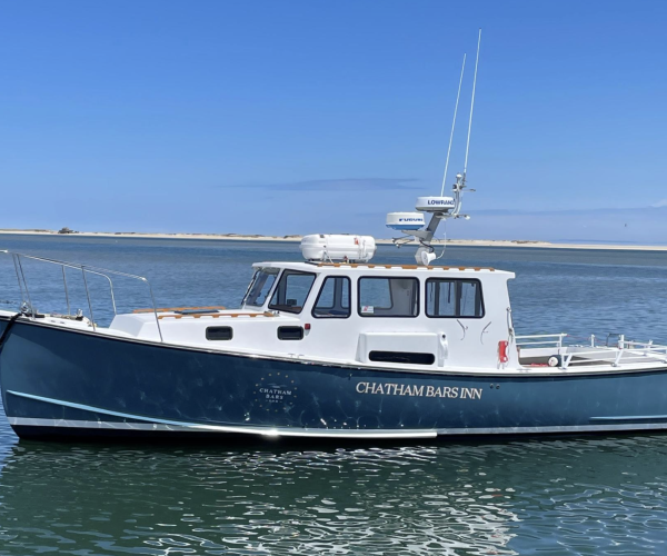 A blue and white boat named "Chatham Bars Inn" is anchored on a calm body of water.